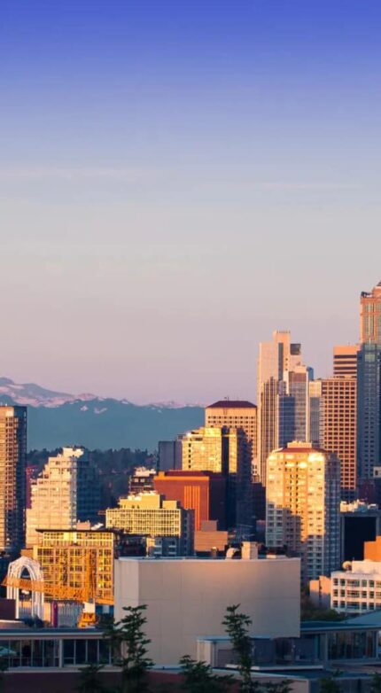 Seattle skyline with the Space Needle in the foreground and Mount Rainier in the background under a clear sky.