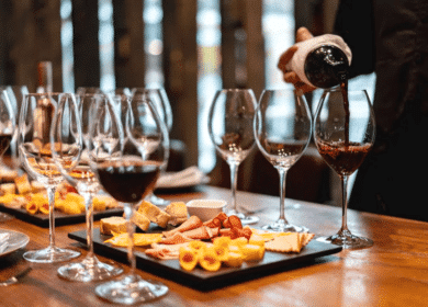 A person pours red wine into a glass beside a table set with multiple wine glasses and platters of assorted cheeses and meats—perfect inspiration for wine tasting experiences among the many things to do in Seattle.